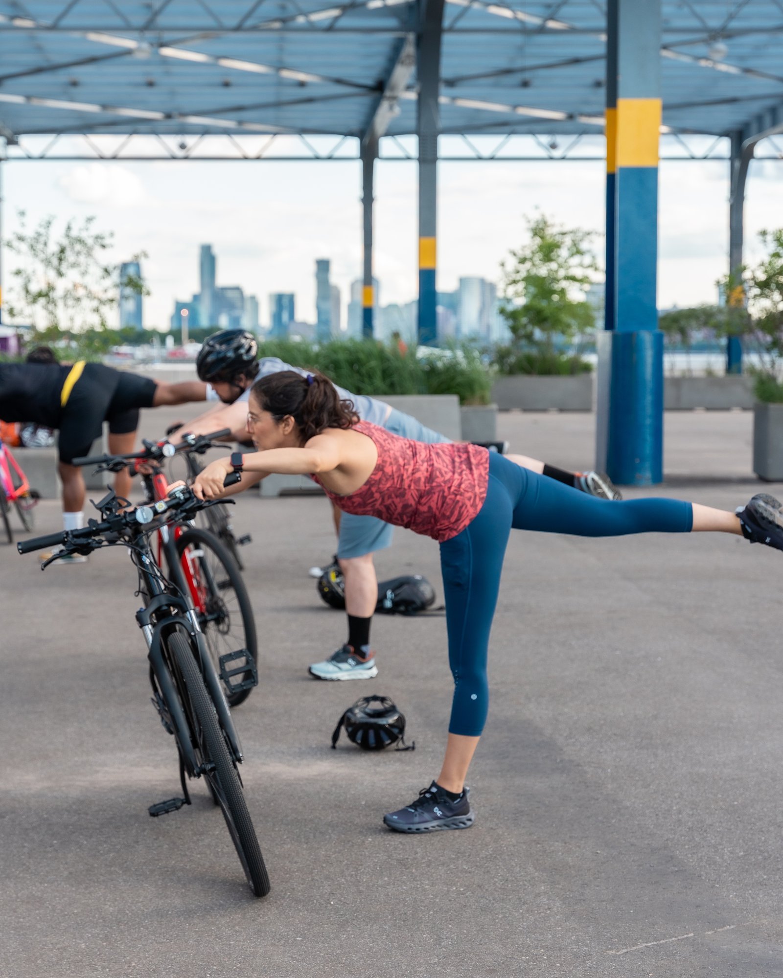 Cyclist balancing in a standing yoga pose using a bike for support, Manhattan skyline in the background