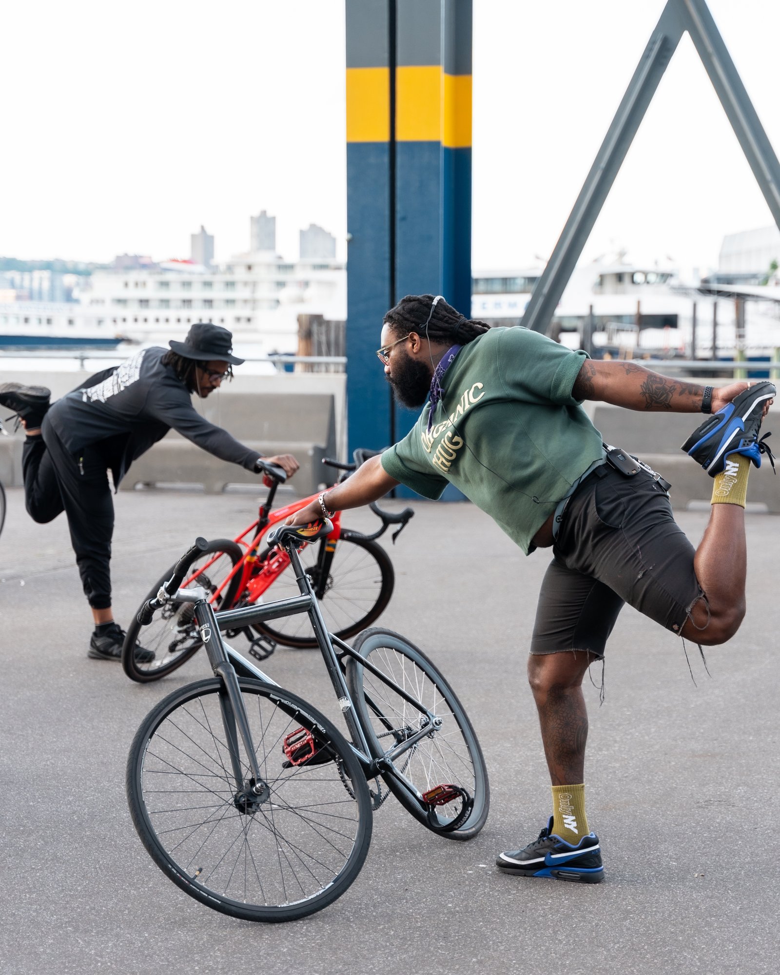 Cyclist using a bike to balance in a standing quad-stretch pose