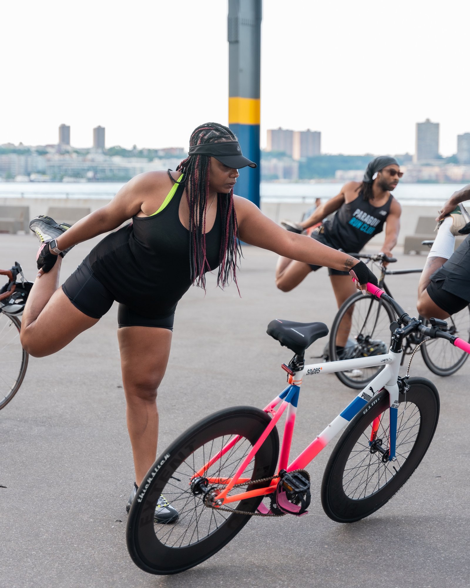 Cyclist using a bike to balance in a standing yoga pose with leg raised