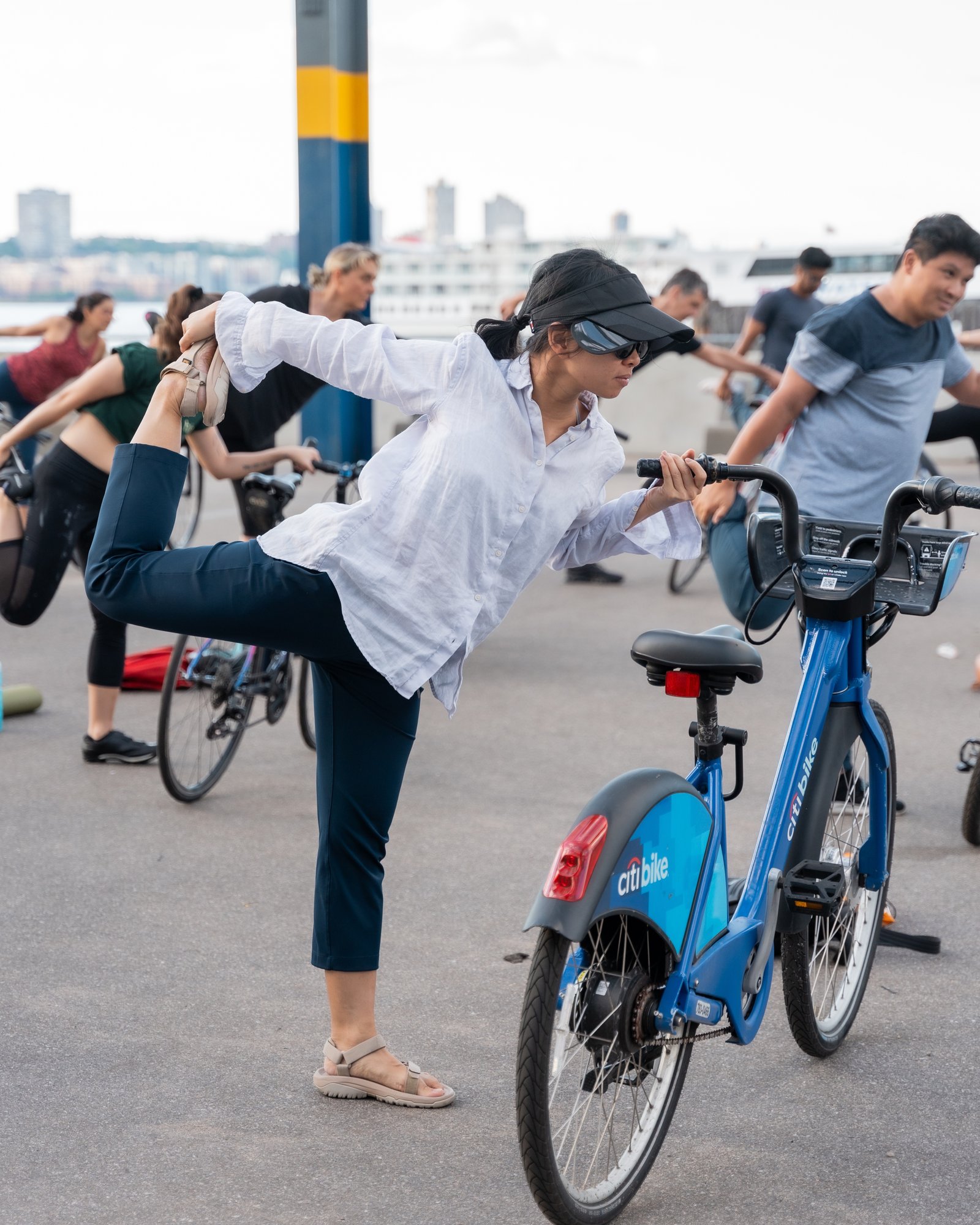 Cyclist using a Citi Bike to balance in a standing split stretch