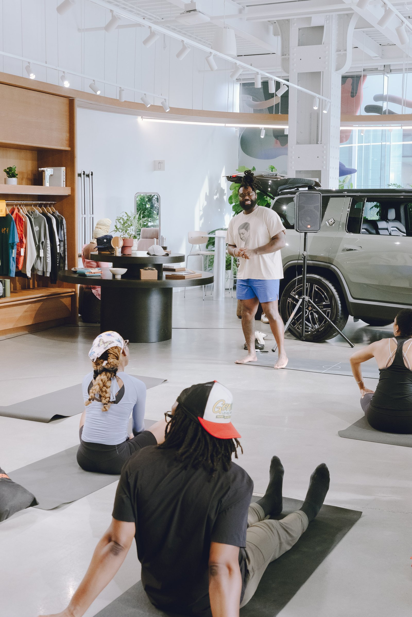 Speaking to a seated group during a yoga session inside the Rivian showroom