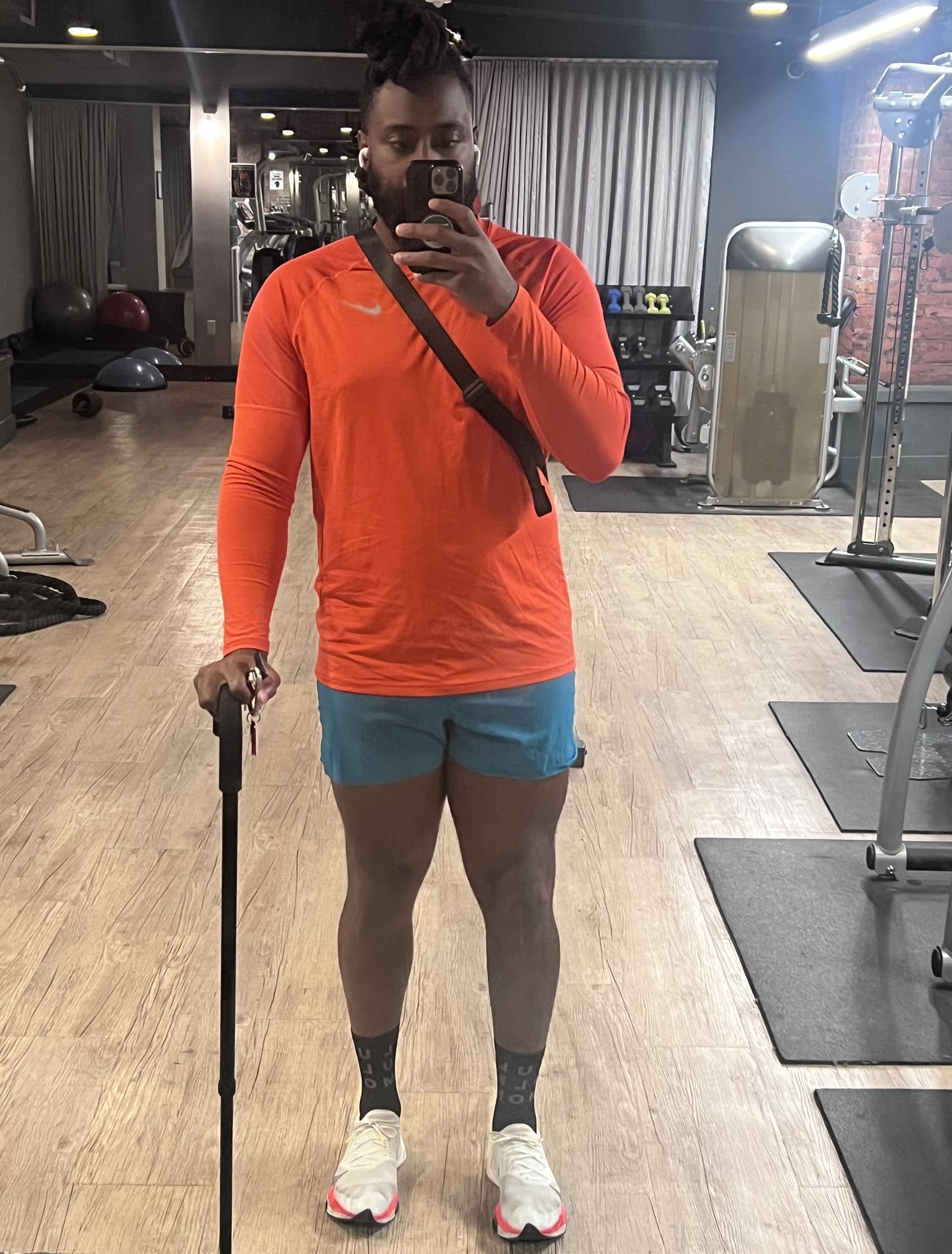 Mirror selfie in a gym, using a cane to stand