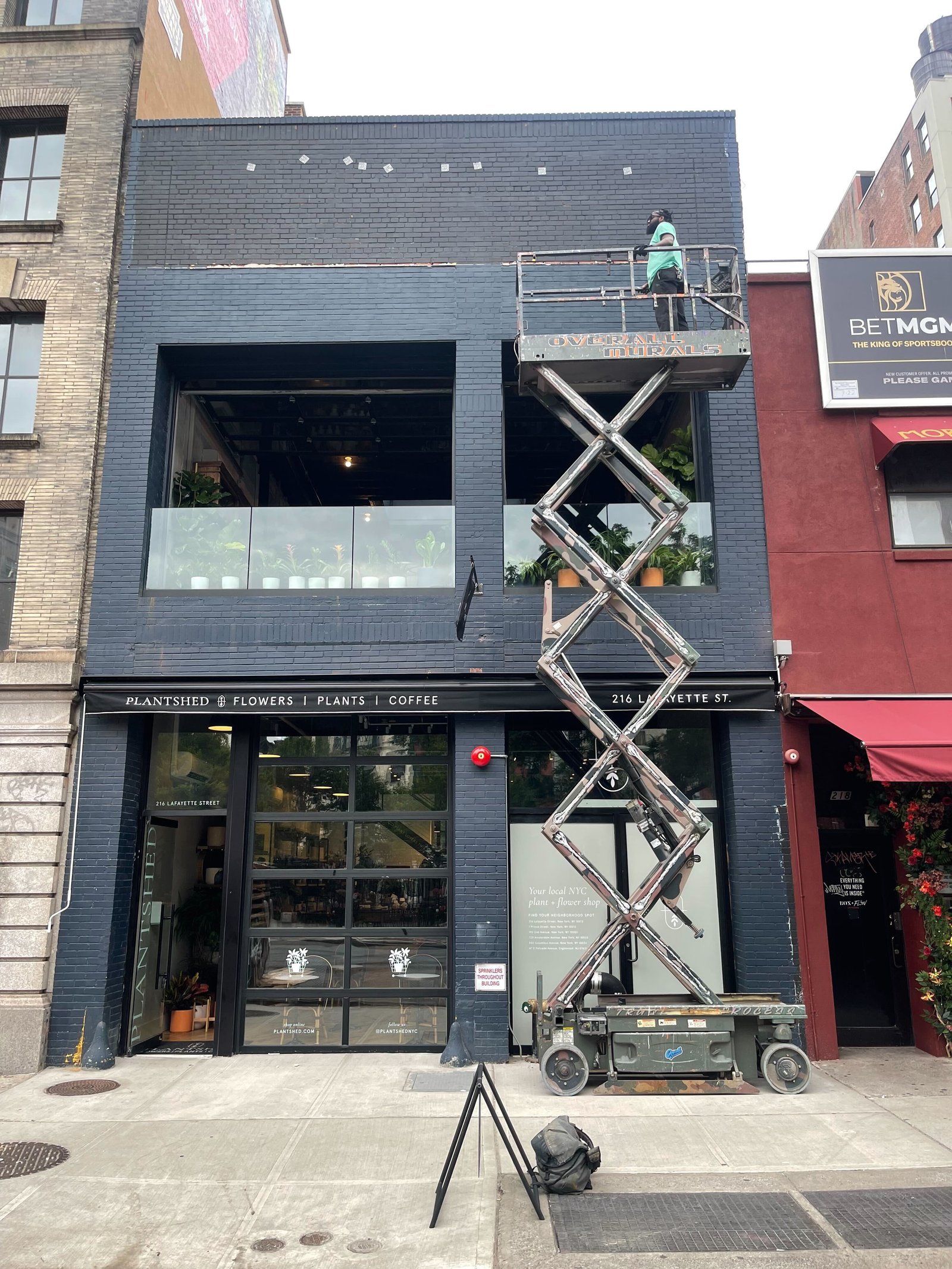 Overall Murals scissor lift painter working on the Plantshed storefront in NYC